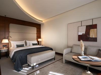 Modern eingerichtetes Hotelzimmer mit gemütlichem Bett, Sofa und stilvoller Beleuchtung.
