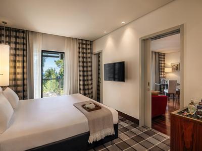 Modern eingerichtetes Hotelzimmer mit großem Bett, Flachbildschirm und Blick auf Balkon.