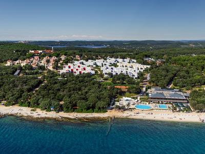 Hotelanlage mit weißem Strand, Pool und bewaldeter Umgebung an der Küste.
