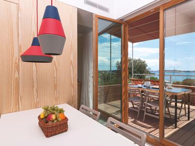 Moderner Essbereich mit bunten Lampen und Aussicht auf Terrasse und Meer.