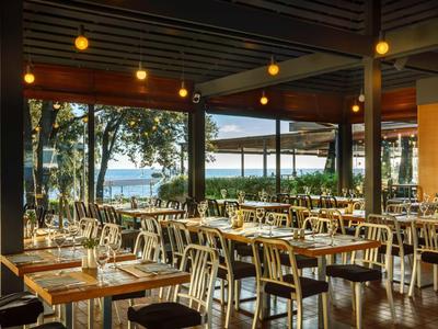 Modern restaurant met houten meubels en uitzicht op het meer bij schemerlicht.