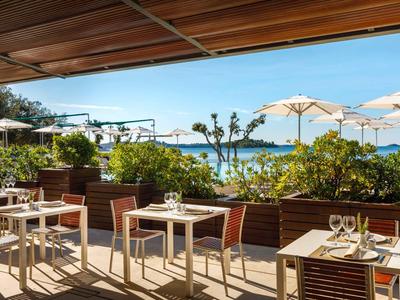 Terras van een restaurant met tafels, stoelen en zeezicht bij zonnig weer