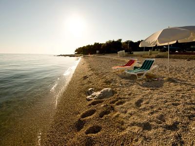 Strand met parasols en ligstoelen bij kalme zee tijdens zonsondergang