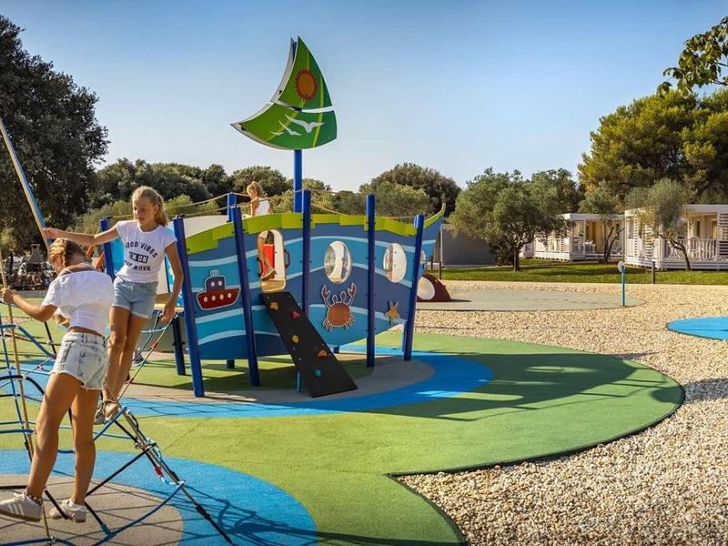 Dzieci bawiące się na kolorowym placu zabaw z drabinkami na świeżym powietrzu.