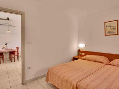 Prosta sypialnia z dwoma łóżkami i widokiem na stół jadalny w sąsiednim pokoju.