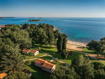 Grüne Hotelanlage an der Küste mit kleinen Häusern und Blick auf das blaue Meer.
