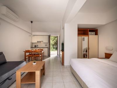Moderner Hotelzimmer-Mix mit Bett, Sofa, Esstisch und Zugang zu einer Terrasse.