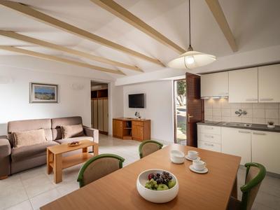 Helles Wohnzimmer mit Sofa, Esstisch und moderner Kücheneinrichtung in Ferienwohnung.