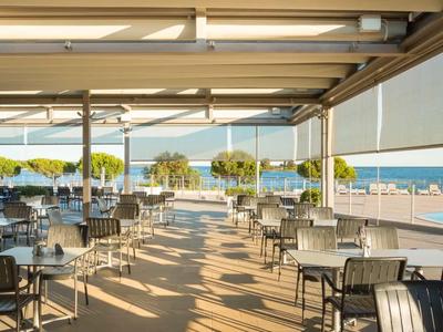 Nowoczesna zadaszona część na zewnątrz restauracji z widokiem na basen i morze.