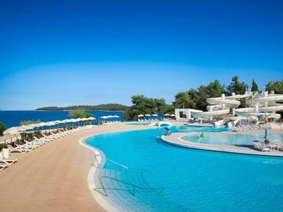 Duży basen z leżakami i zjeżdżalniami w hotelu nad morzem.