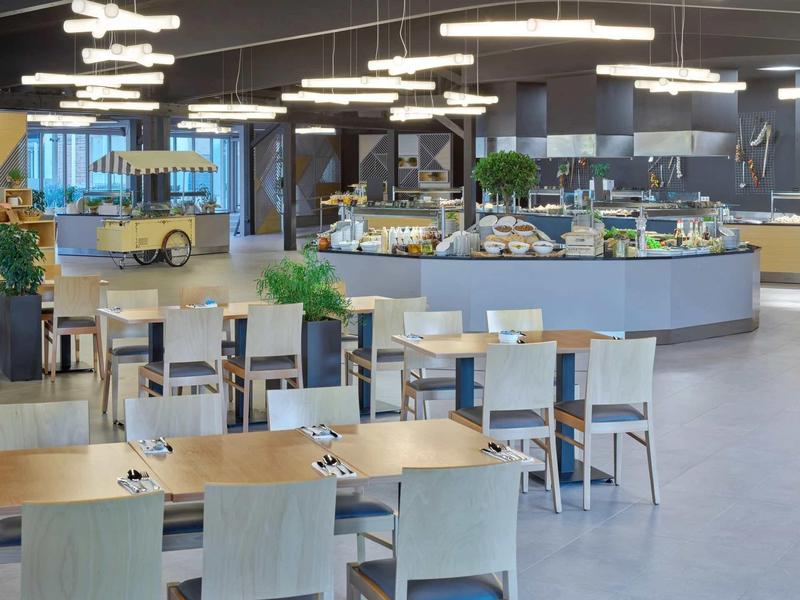 Nowoczesna restauracja hotelowa z drewnianymi krzesłami i oświetlonym bufetem.