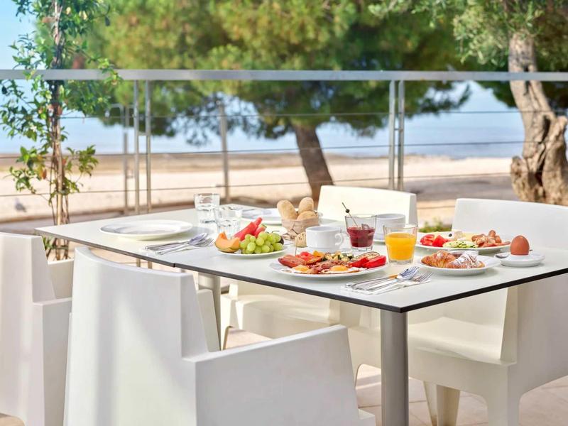 Stół z śniadaniem i napojami na tarasie z widokiem na plażę i morze