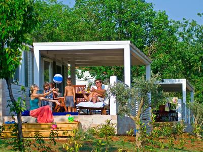 Mensen genieten van het terras van een modern vakantiehuis omgeven door bomen.