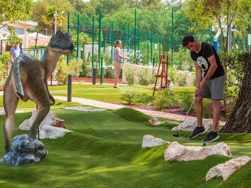 Man speelt minigolf op een met gras bedekte baan met een groot kangoeroebeeld.