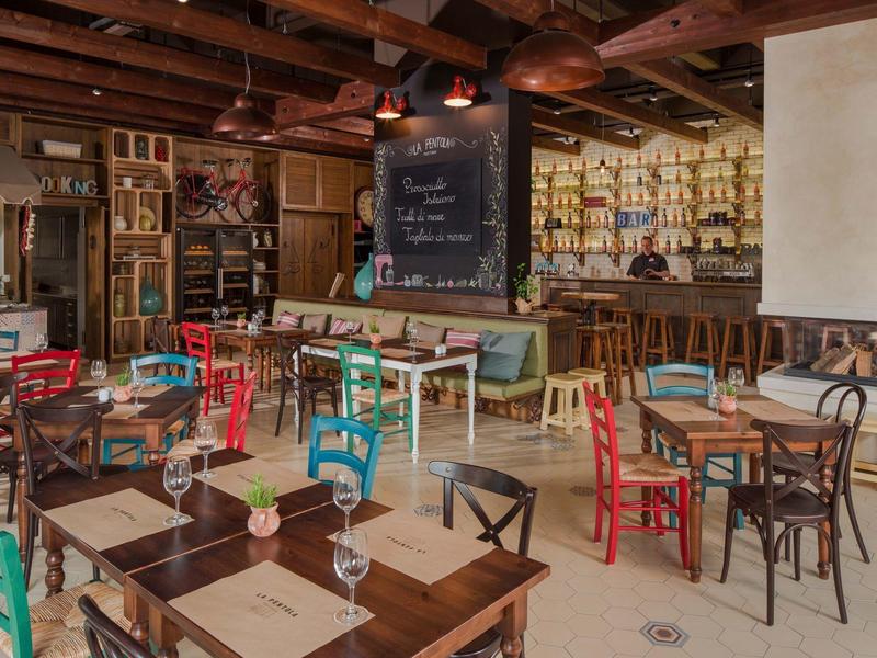 Kleurrijk gezellig café met houten meubels en decoratieve boekenplank aan de muur.