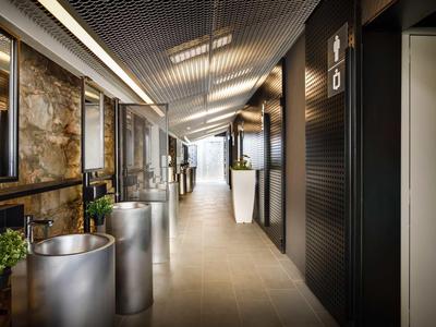 Corridoio d'hotel moderno con design industriale, piante e illuminazione elegante.