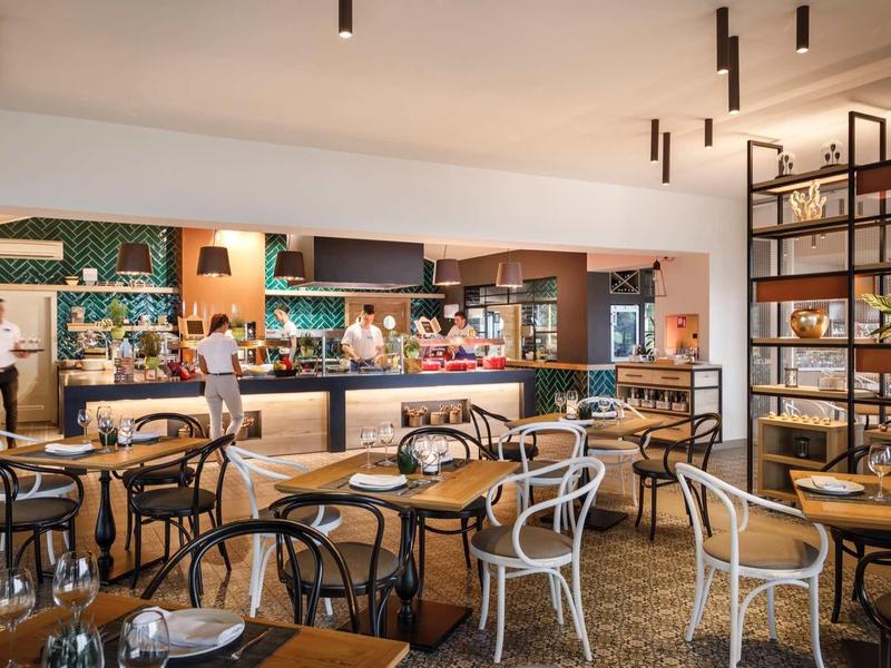 Restaurante moderno de hotel con mesas elegantes, sillas y área de buffet abierta.