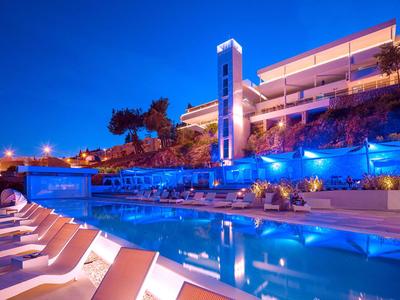 Moderner Poolbereich eines Hotels mit Liegestühlen und blauem Beleuchtung bei Nacht.