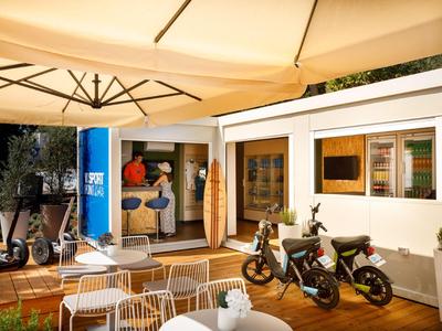 Terrasse mit weißen Stühlen, Sonnenschirm, Rollern und offenem Raum mit sportlichen Sachen