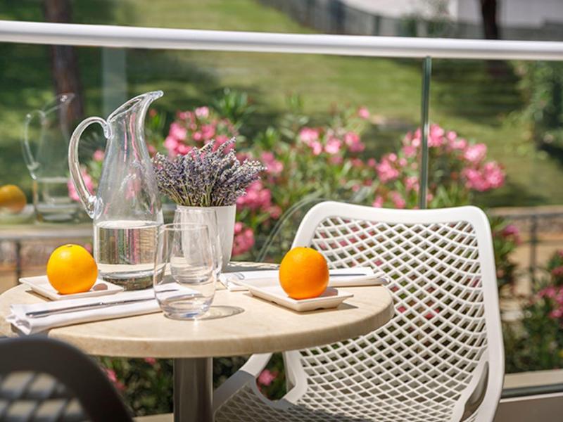 Balcon confortable avec table ronde, deux chaises blanches, oranges et décoration florale.