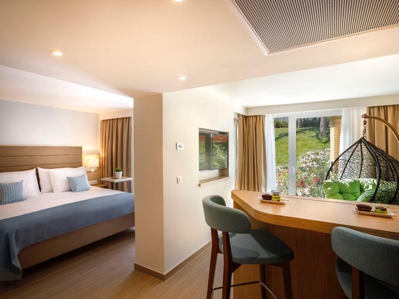 Chambre d'hôtel moderne avec grand lit et coin salon près de la fenêtre avec vue.