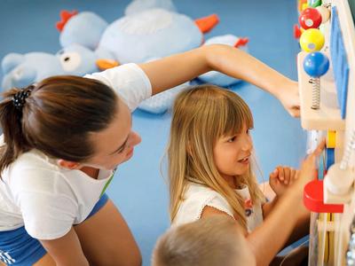 Una mujer y un niño juegan juntos con un juego de pared colorido en un interior.