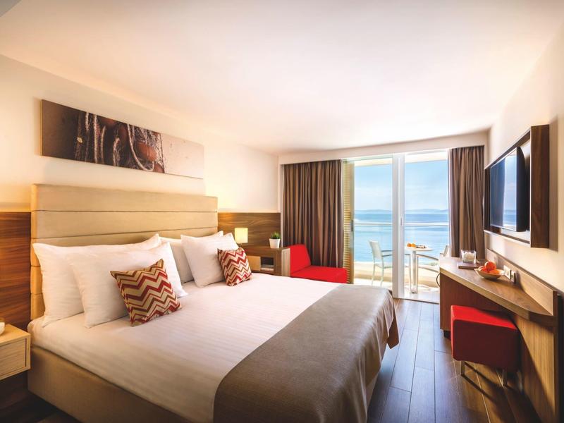 Habitación de hotel moderna con cama doble, gran ventana y vista al mar.