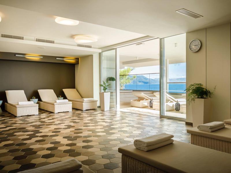 Sala de bienestar moderna con tumbonas y vista al mar a través de grandes ventanas.