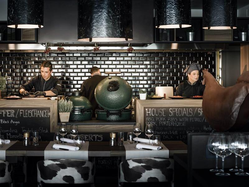 Bar de hotel moderna con bartenders, pared de azulejos negros y detalles decorativos interiores.