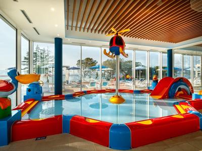 Área de juegos interior colorida y segura para niños con toboganes y equipos de escalada en un hotel.
