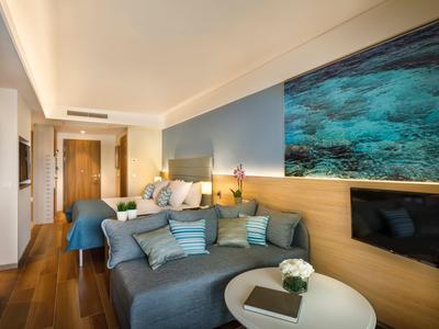 Habitación de hotel moderna con sofá, cama y gran foto submarina en la pared.