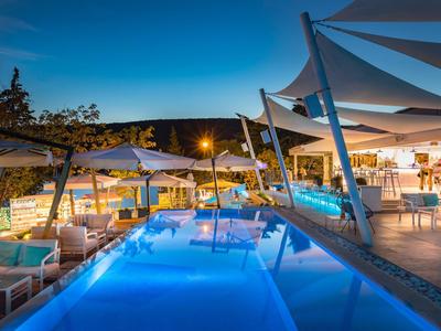 Nowoczesny, oświetlony basen z miejscami do siedzenia i parasolami o zmierzchu