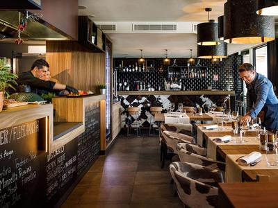 Restauracja w hotelu z nakrytymi stolikami i personelem przygotowującym się.