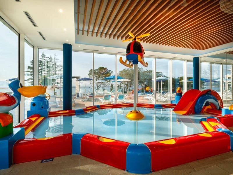 Área de juegos interior colorida y segura para niños con toboganes y equipos de escalada en un hotel.