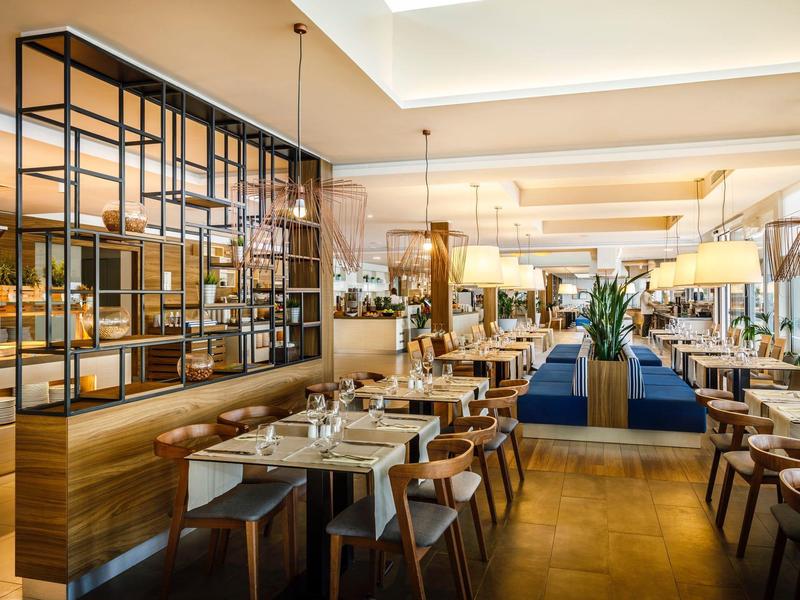 Restaurante moderno y luminoso con mesas elegantemente preparadas y decoración con estilo.