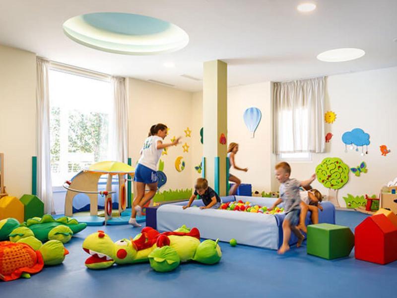 Sala de juegos colorida para niños con juguetes y niños jugando adentro.