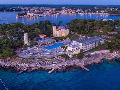 Luxe kustresort met zwembad en havenzicht bij zonsondergang.