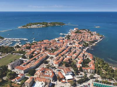 Luchtfoto van een kustplaats met rode daken en een kleine haven aan de zee