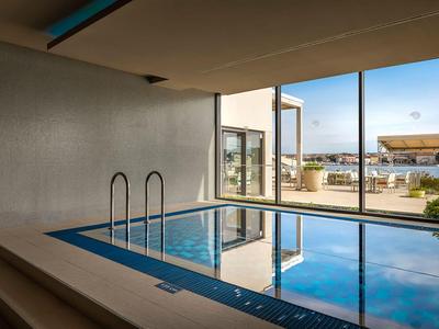 Kryty basen z dużymi oknami, widok na taras i teren zewnętrzny w świetle dziennym.