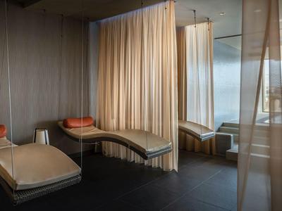 Rustige wellnessruimte met drie ligbedden, gordijnen en uitzicht op het water.