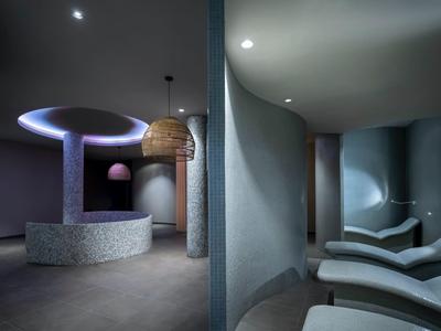 Moderne spa-lounge met gebogen muren, ontspannende verlichting en comfortabele ligstoelen.
