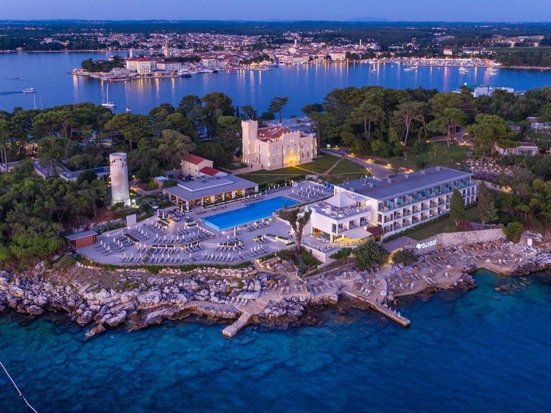 Luxe kustresort met zwembad en havenzicht bij zonsondergang.