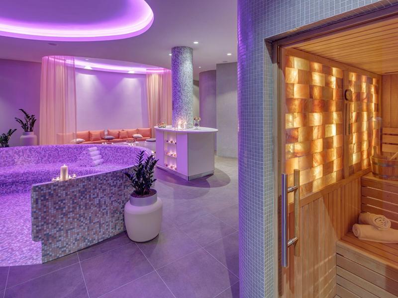Moderne wellnessruimte met jacuzzi, sauna en rustgevende verlichting.