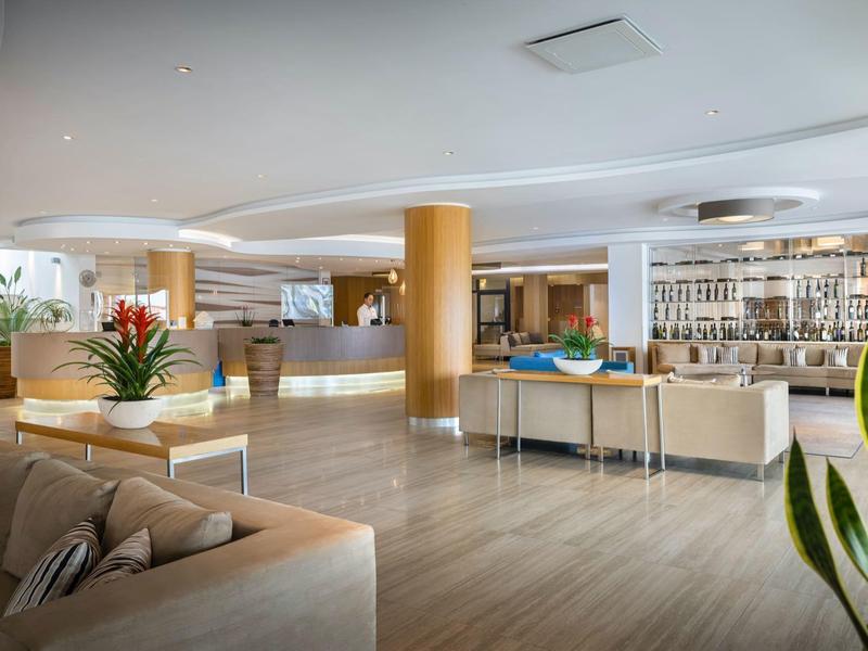 Moderne hotel lobby met bar, comfortabele zitplaatsen en decoratieve planten.