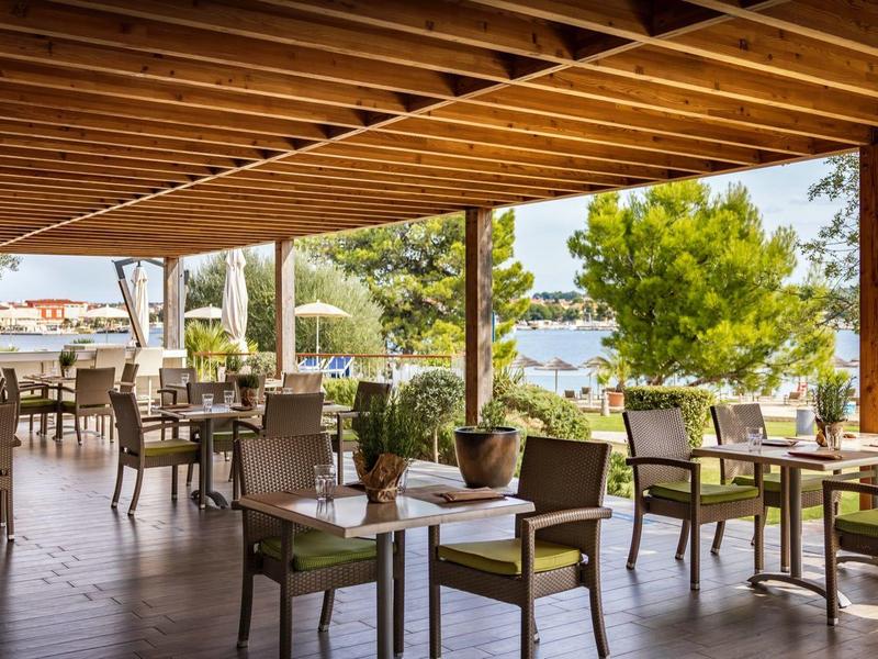 Overdekt buitenterras met houten balkenplafond en uitzicht op de haven.