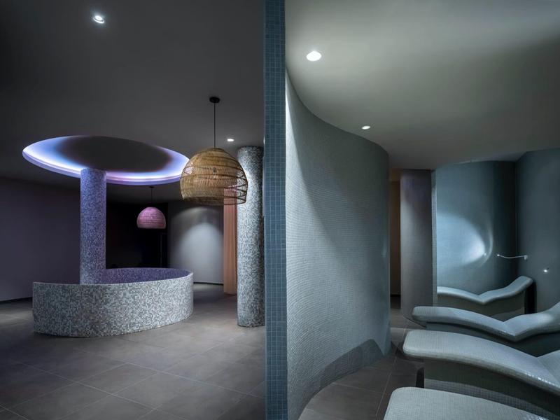 Moderne spa-lounge met gebogen muren, ontspannende verlichting en comfortabele ligstoelen.