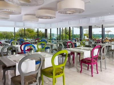 Restaurant moderne avec chaises colorées et grandes fenêtres donnant sur la verdure.