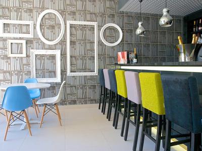 Espace bar moderne avec des chaises colorées et des cadres vides au mur.