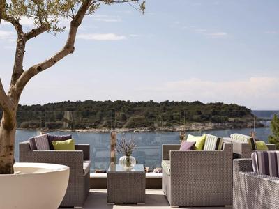 Salon extérieur moderne avec vue sur la mer et des arbres en arrière-plan.