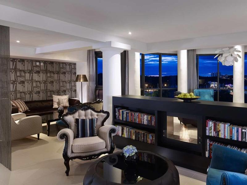 Modern hotel lounge area with comfortable armchairs and bookshelves in evening light.
